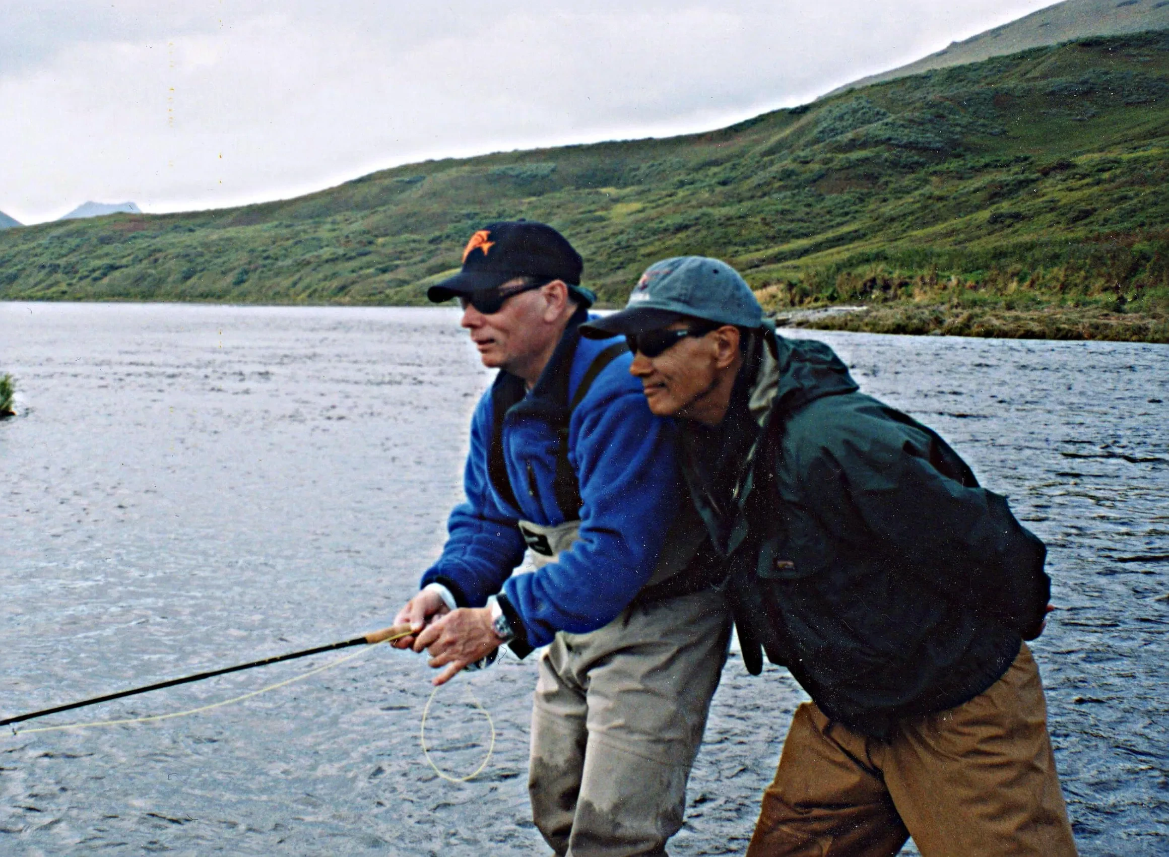 Bill Ward teaching a student fly fishing technique outdoors